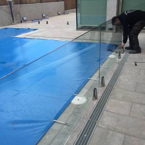 trabajador colocando cerramiento de cristal en piscina