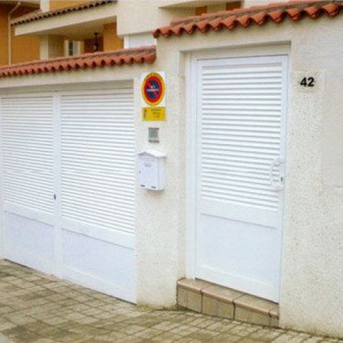 Puerta de garaje y entrada en chalet en color blanco