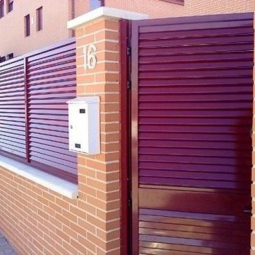 Valla exterior y puerta de acceso a vivienda en color granate