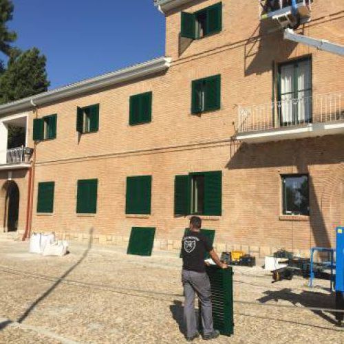 Fachada con persianas verdes colocadas y grúa con trabajador