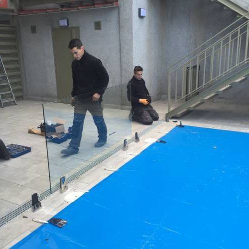 trabajadores colocando cerramiento de cristal en piscina